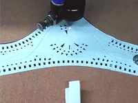 Nority Laser cutter cuts openwork in double headed white leather.
